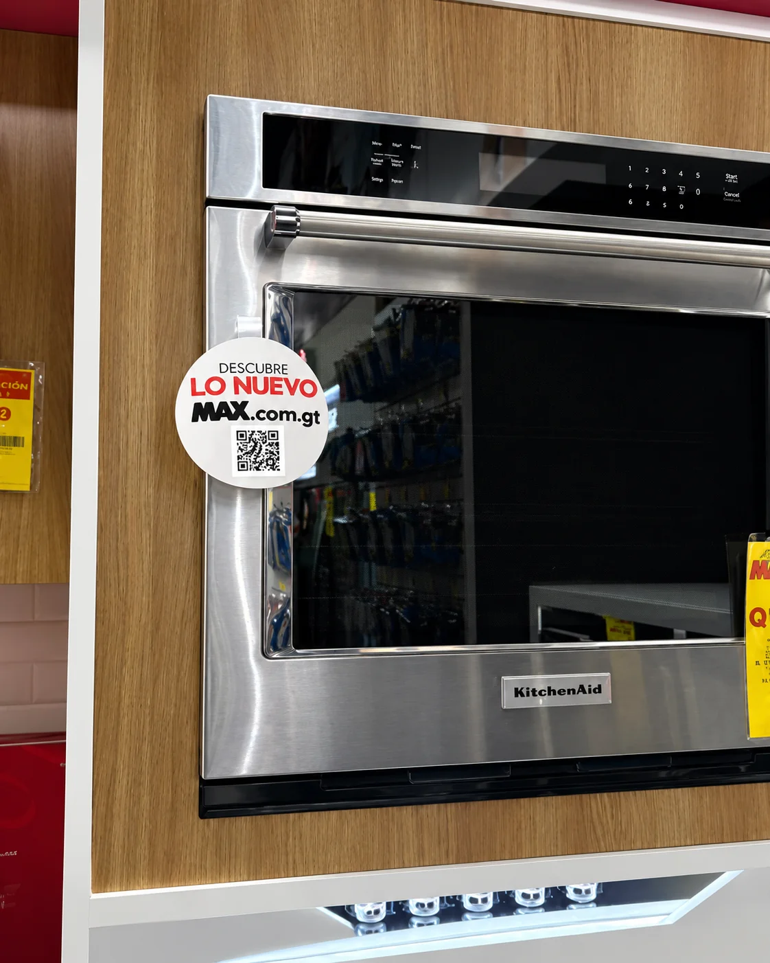 Dangler circular con un código QR de MAX junto a un horno en tienda